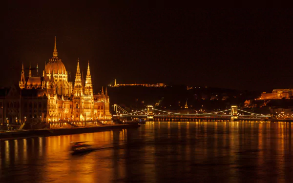 HD wallpaper of Budapest at night, featuring a luminous view of the Hungarian Parliament building and the Chain Bridge over the Danube River.
