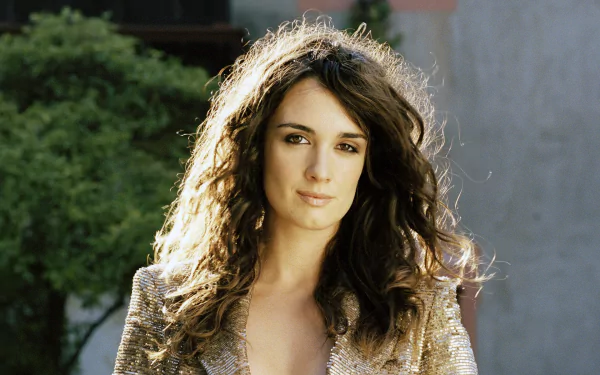 HD desktop wallpaper featuring Spanish actress and celebrity Paz Vega outdoors with natural lighting and greenery in the background.