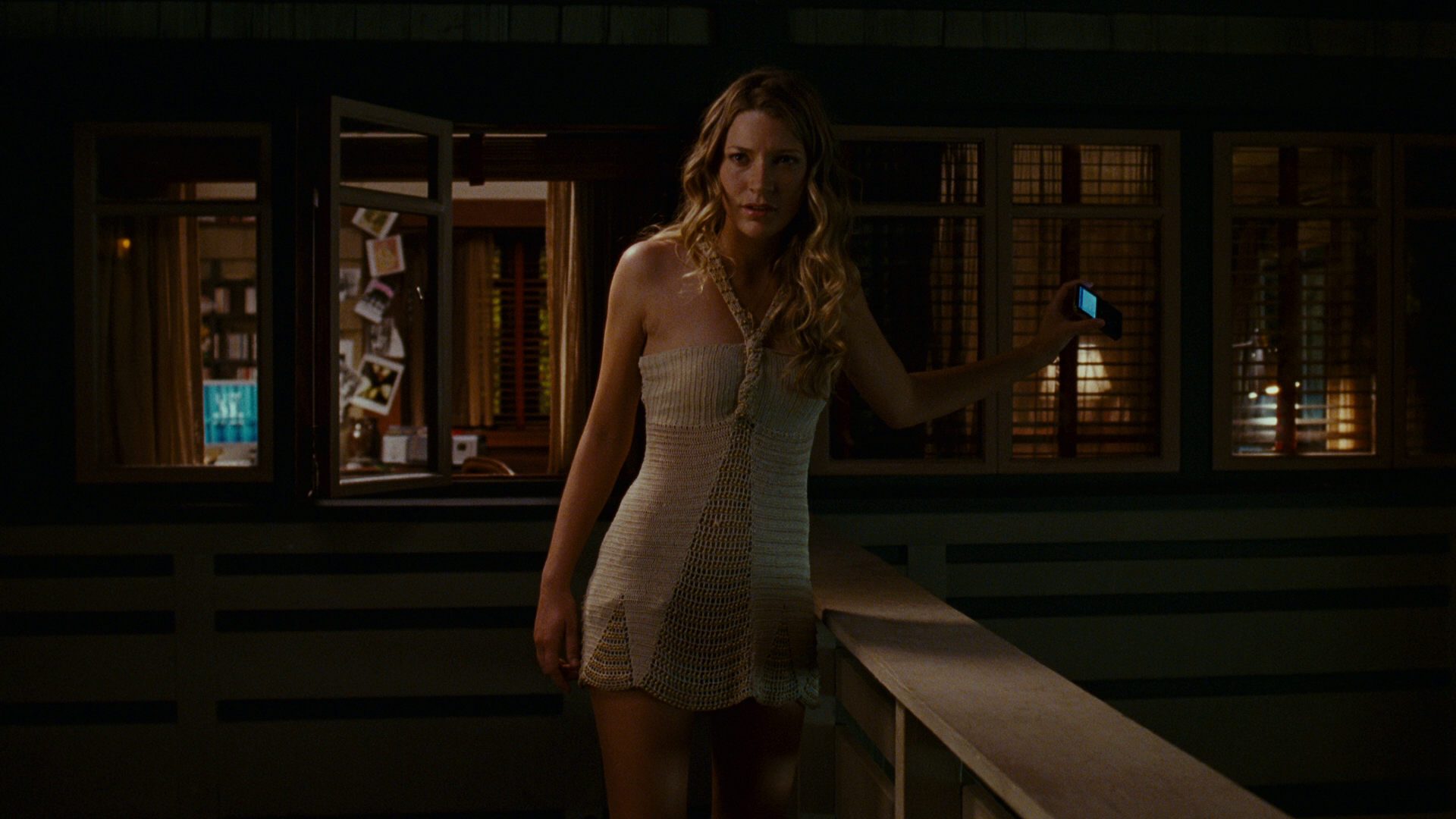 HD PC desktop wallpaper from the movie Disturbia featuring a woman in a light dress standing on a dimly lit porch at night.
