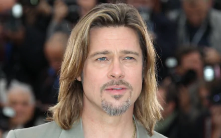 4K Ultra HD PC desktop wallpaper: close-up of a fair-skinned man with shoulder-length blond hair and trimmed goatee, wearing a blazer, neutral expression with a blurred crowd in the background.