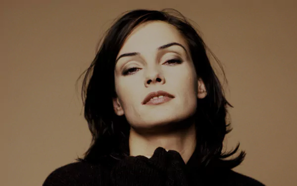 Portrait of Dutch actress Famke Janssen with a neutral expression, set against a plain brown background in HD quality.