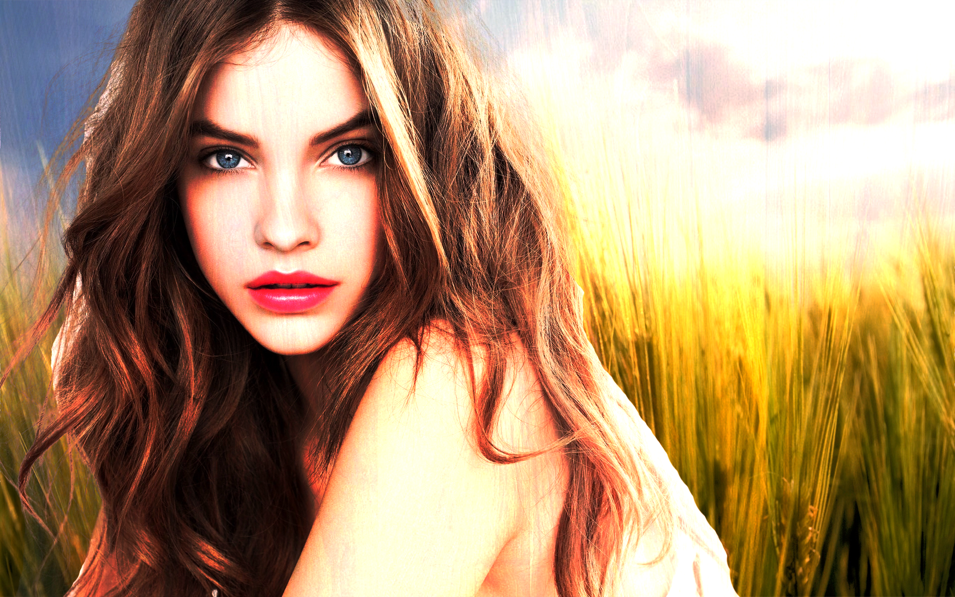 A striking HD desktop wallpaper featuring celebrity Barbara Palvin, with her captivating gaze framed by waves of hair against a vibrant natural background.