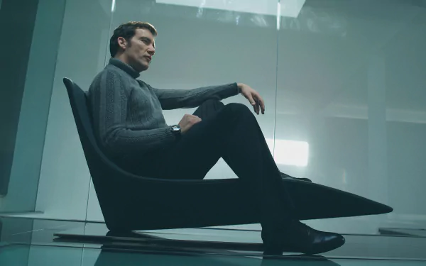 Cinematic 2K Quad HD PC desktop wallpaper: a man in a dark turtleneck reclines in a low modern chair inside a minimalist glass-walled room, moody lighting and reflective floor.