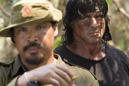 HD desktop wallpaper showing a scene from the movie Rambo with a soldier in focus and another character in the background, both displaying intense expressions.