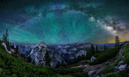 A stunning view of Yosemite National Park showcasing a starry sky filled with vibrant colors over majestic mountains, creating a breathtaking natural scene for your desktop wallpaper.