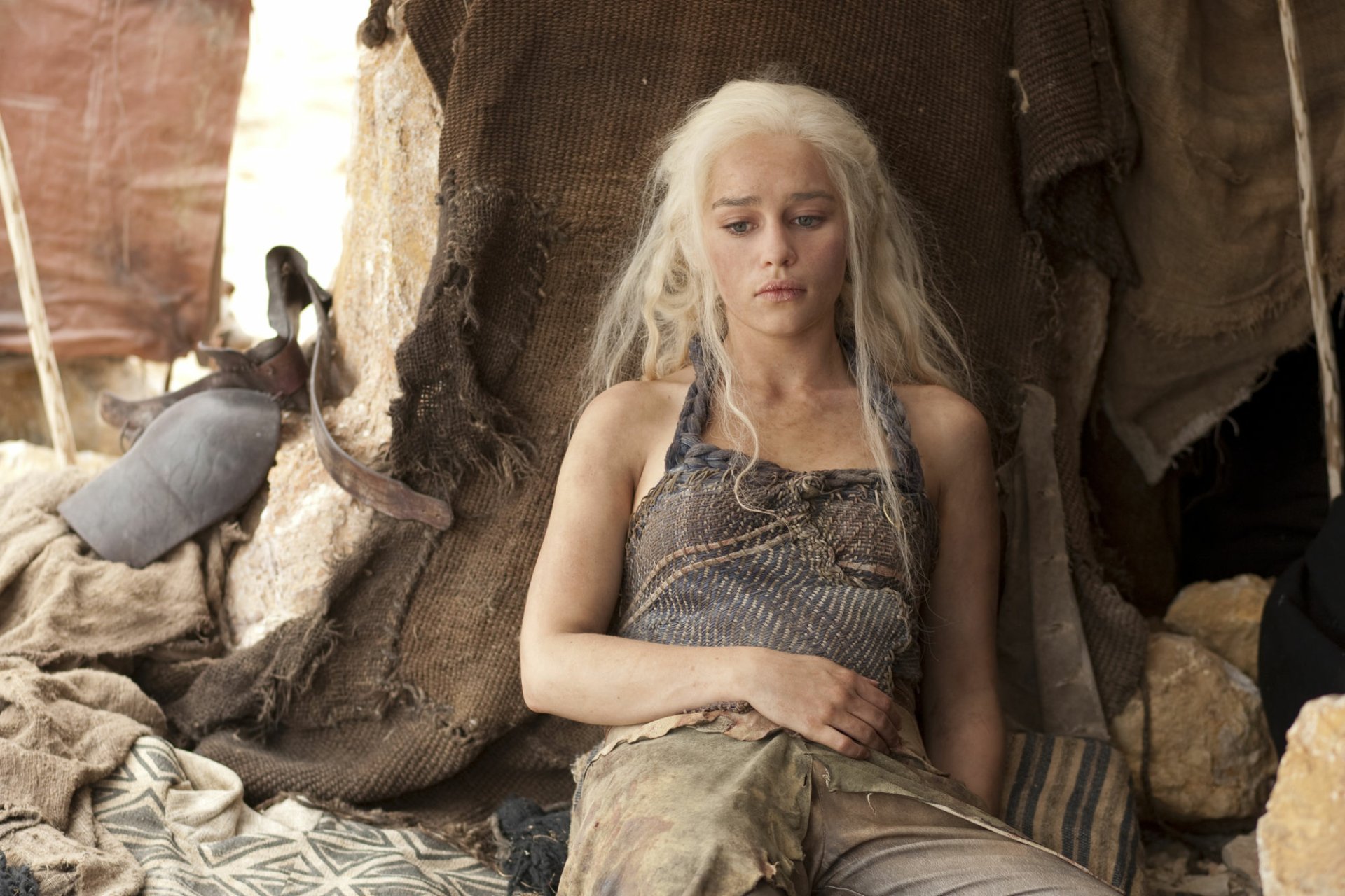 TV-show character with long platinum hair in a sunlit tent, wearing a worn tunic, seated and pensive — HD PC desktop wallpaper/background.