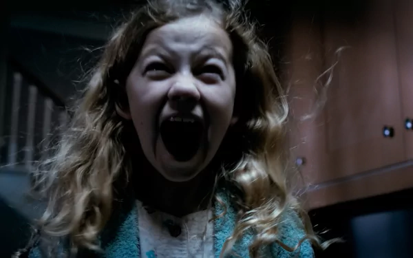 A high-definition wallpaper featuring Megan Charpentier in a chilling scene from the movie Mama, capturing intense emotion with her screaming expression against a dark background.