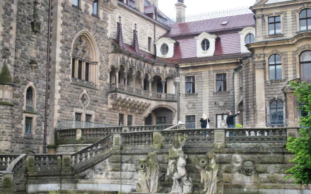 Man-made Moszna Castle courtyard with ornate stone staircases, sculptures and greenery — HD PC desktop wallpaper/background.