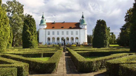 Baranów Sandomierski Castle, a man-made Baroque chateau centered beyond formal hedged gardens under a cloudy sky — 2K Quad HD PC desktop wallpaper/background.
