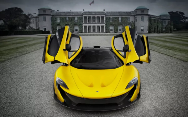 HD desktop wallpaper featuring a bright yellow McLaren P1 with its doors raised, parked on a gravel driveway in front of a grand historic mansion.