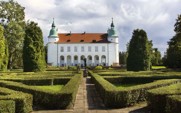 Baranów Sandomierski Castle, a man-made Baroque chateau centered beyond formal hedged gardens under a cloudy sky — 2K Quad HD PC desktop wallpaper/background.