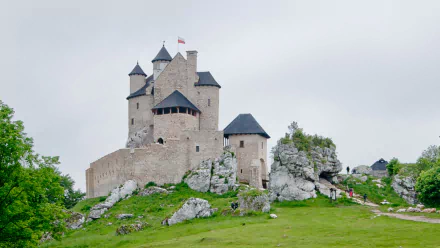 HD desktop wallpaper showcasing the man-made Bobolice Castle perched on rocky terrain under a cloudy sky.