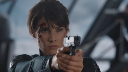 Maria Hill, portrayed by Cobie Smulders, aims her gun with determination in this HD Avengers movie wallpaper, showcasing her fierce character in a dynamic action scene.