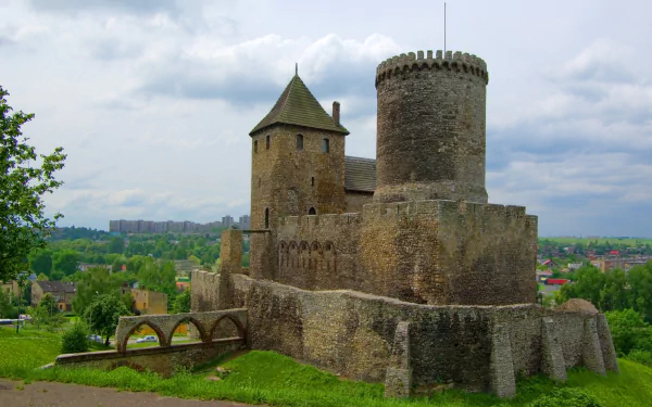 HD PC desktop background of Bedzin Castle, a man-made medieval stone fortress on a grassy hill beneath a cloudy sky.
