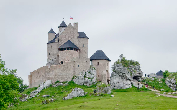 HD desktop wallpaper showcasing the man-made Bobolice Castle perched on rocky terrain under a cloudy sky.