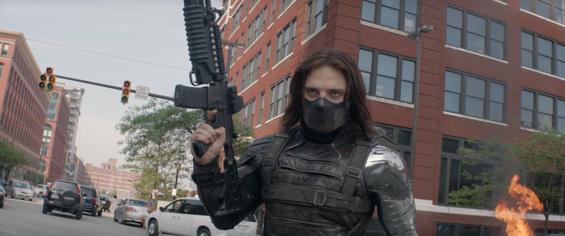Sebastian Stan as the Winter Soldier, featuring his iconic armored look and weapon, set against a city backdrop from the movie Captain America: The Winter Soldier. HD desktop wallpaper.