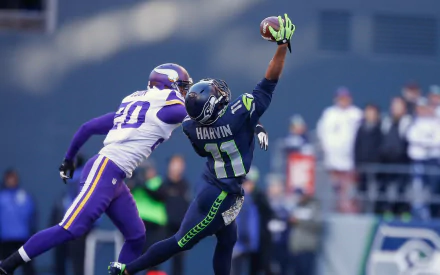 Seattle Seahawks player catching a football while a Minnesota Vikings defender attempts to block, shown in this HD PC desktop wallpaper and background.