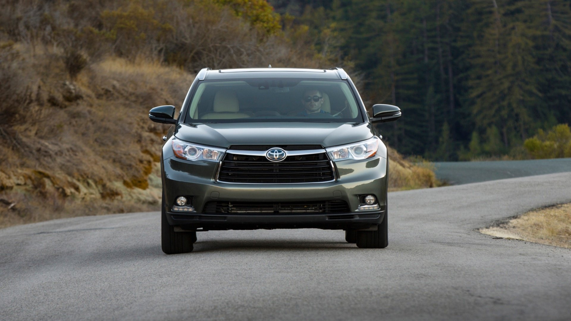 Front view of a Toyota Highlander Hybrid SUV on a winding rural road, HD PC desktop wallpaper/background.