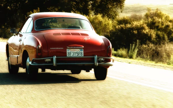 Rear view of a red Volkswagen Karmann Ghia cruising a sunlit country road — 2K Quad HD PC desktop wallpaper and background.