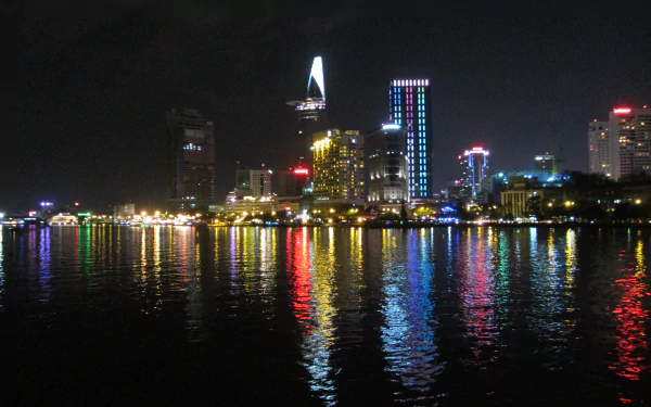 Night view of Ho Chi Minh City's skyline featuring the Bitexco Financial Tower reflecting on the Saigon River in Vietnam.
