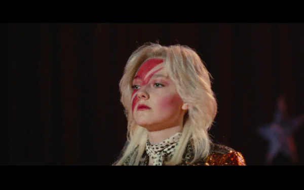 HD PC desktop wallpaper: movie still from The Runaways — a blonde performer with red lightning face paint and sequined jacket standing on a dark stage backdrop.