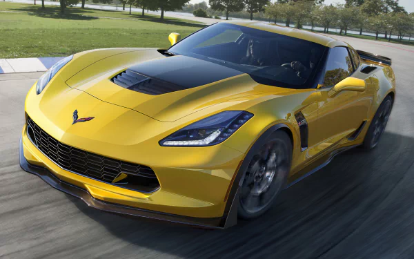 HD PC desktop wallpaper featuring a sleek yellow Chevrolet Corvette speeding on a road with a green park and trees in the background.