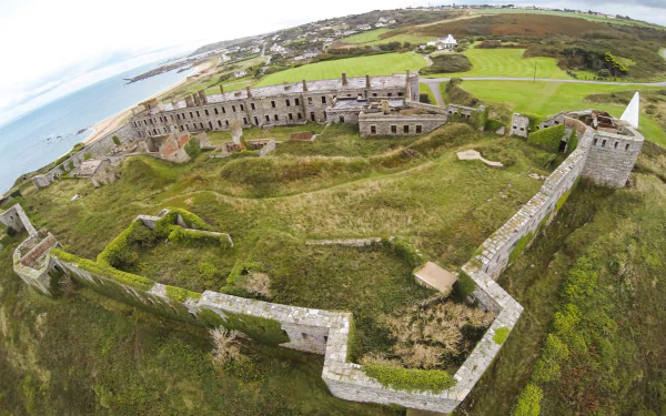Aerial view of man made Fort Tourgis on a coastal headland, crumbling stone bastions and green ramparts, 2K Quad HD PC Desktop Wallpaper and Background.