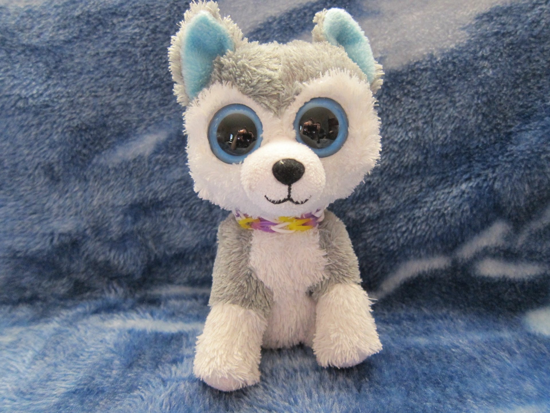 HD desktop wallpaper featuring a man-made Beanie Boos plush toy resembling a gray and white husky with large, blue-rimmed eyes on a soft blue background.