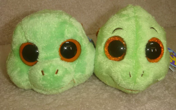 HD desktop wallpaper featuring two green Beanie Boos with large orange-rimmed eyes, showcasing their soft, plush man-made design.