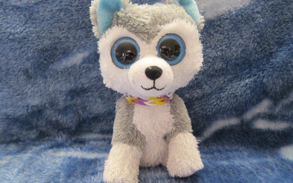 HD desktop wallpaper featuring a man-made Beanie Boos plush toy resembling a gray and white husky with large, blue-rimmed eyes on a soft blue background.