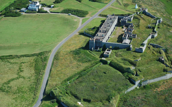 Aerial view of man-made Fort Tourgis on a grassy headland with stone walls and access roads — 2K Quad HD PC desktop wallpaper and background.