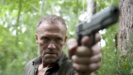 Merle Dixon from *The Walking Dead* aims a handgun confidently in a dense forest, showcasing the intense atmosphere of the TV show's post-apocalyptic world.
