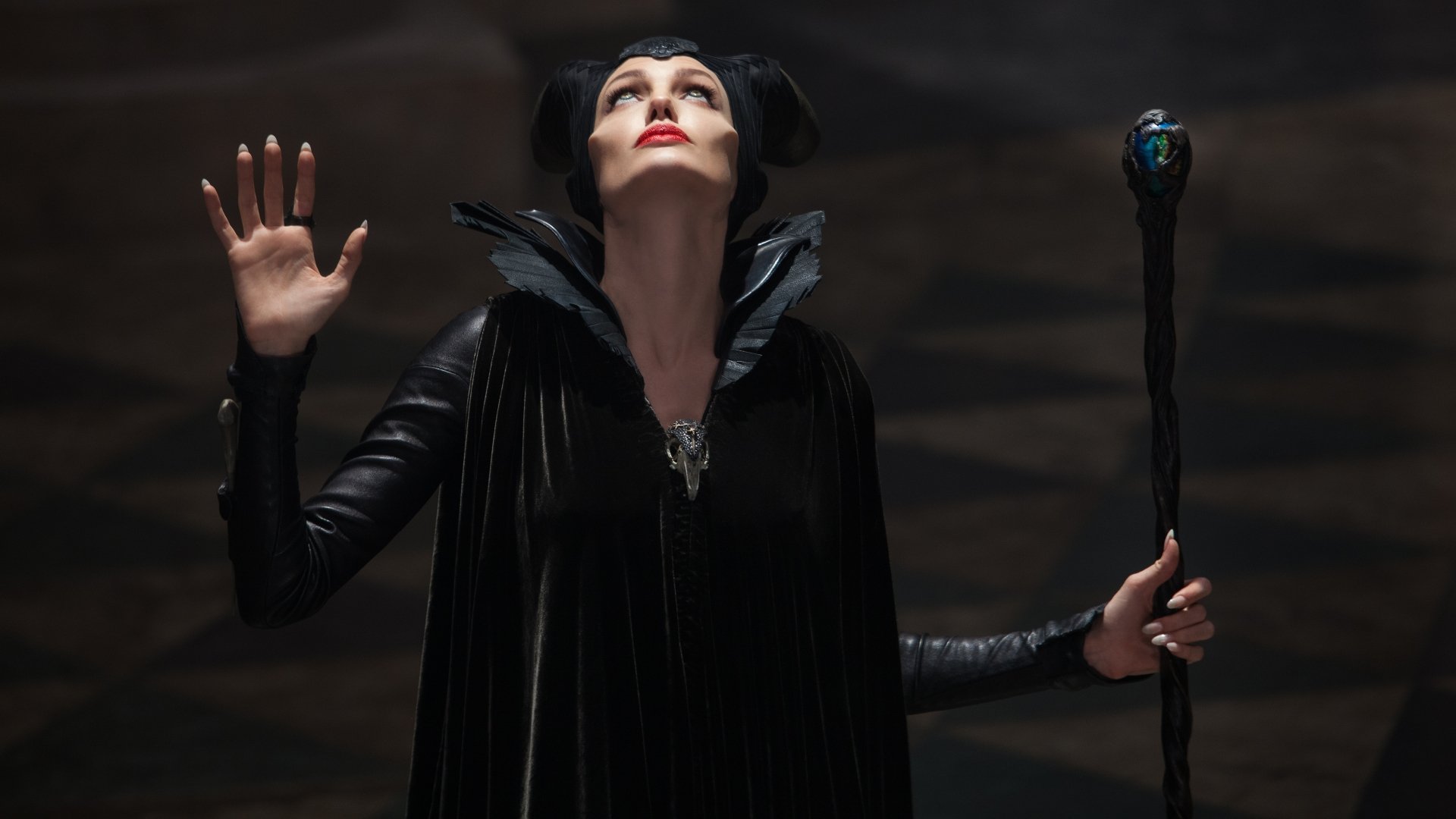 5K Ultra HD PC wallpaper from the movie Maleficent: horned, black-cloaked sorceress raises a hand and grips a jeweled staff against a dark, dramatic backdrop.