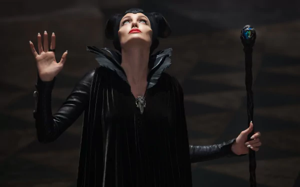 5K Ultra HD PC wallpaper from the movie Maleficent: horned, black-cloaked sorceress raises a hand and grips a jeweled staff against a dark, dramatic backdrop.