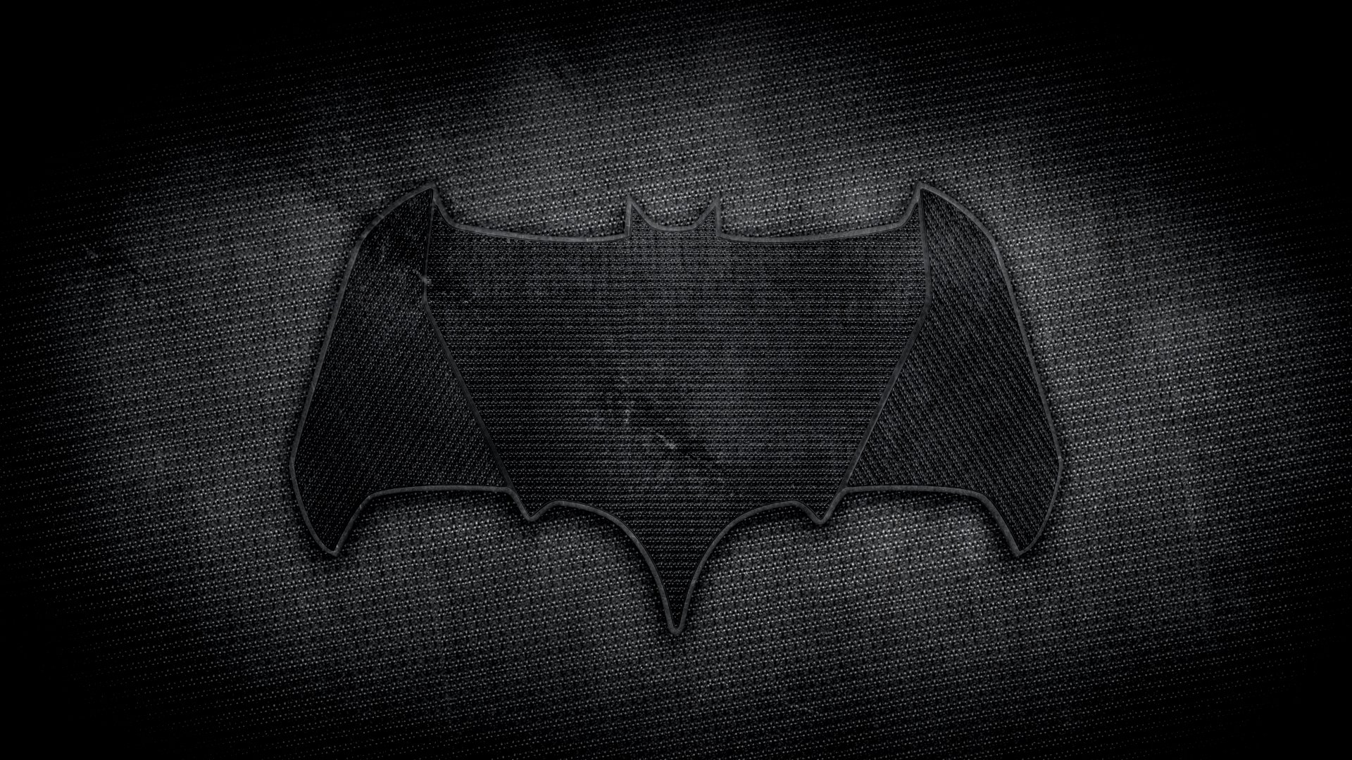 A bold Batman symbol set against a textured dark background, making for a striking HD PC desktop wallpaper that embodies the essence of the iconic comic character.