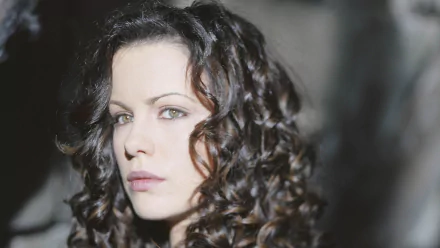 Close-up of Anna Valerious, portrayed by Kate Beckinsale in the movie Van Helsing, showcasing her elegant curls and striking features in a dramatic setting. HD wallpaper background.