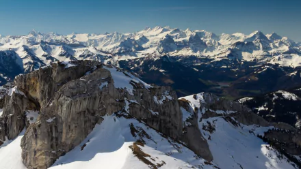 A stunning HD wallpaper showcasing the majestic Alps, featuring snow-capped peaks and rugged rock formations against a clear blue sky, capturing the beauty of nature.