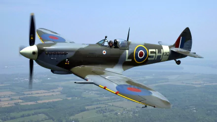 A Supermarine Spitfire flies gracefully through a clear sky, showcasing its iconic design and military heritage, with vibrant roundels adorning its wings. An inspiring HD PC desktop wallpaper.