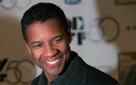 HD desktop wallpaper featuring American actor and celebrity Denzel Washington smiling against a blurred event backdrop.
