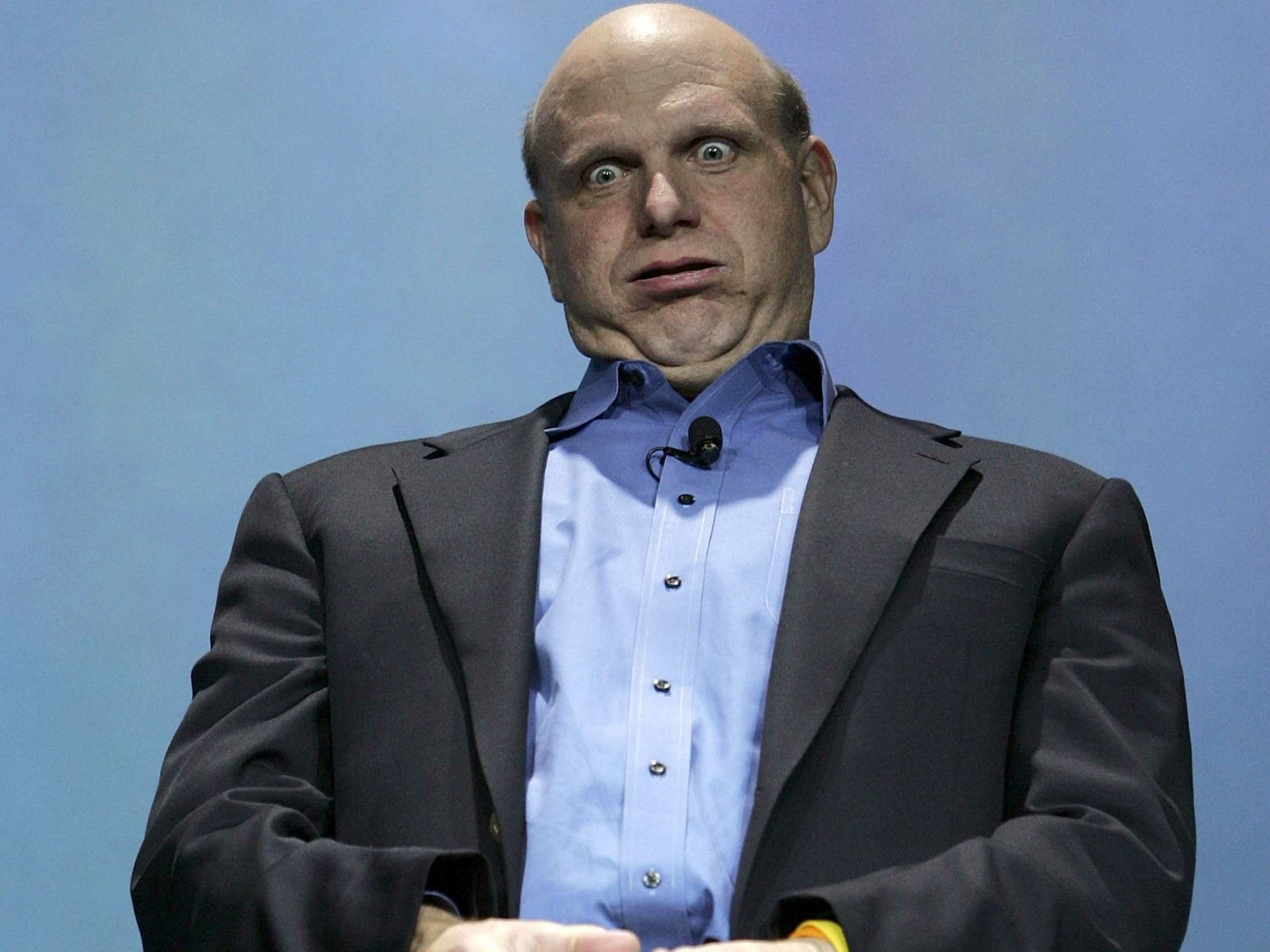 A man in a suit making a surprised facial expression, set against a blue background, serves as an HD desktop wallpaper.