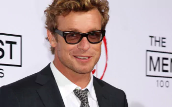 Smiling blond man in a suit and sunglasses on a red carpet, 2K Quad HD PC desktop wallpaper.