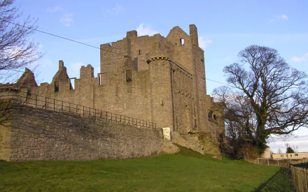 HD desktop wallpaper showcasing the historic man-made Craigmillar Castle against a clear sky with surrounding stone walls and leafless trees.