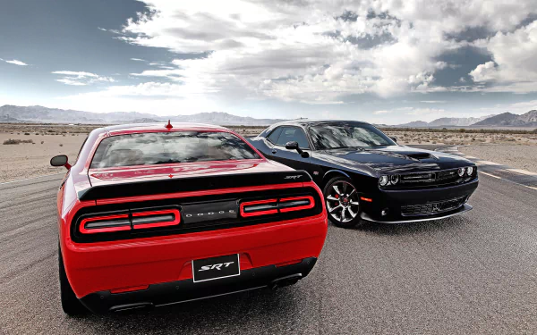 HD desktop wallpaper featuring a red and a black Dodge Challenger SRT Hellcat parked on an open road under a partly cloudy sky.