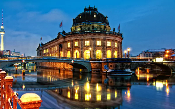 HD wallpaper showcasing the illuminated Bode Museum at twilight, with its reflection glowing on the calm river and a nearby bridge under a clear evening sky.