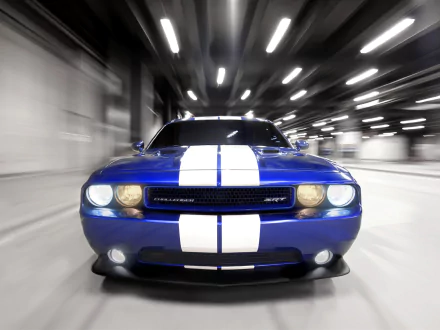 A striking HD wallpaper showing a blue Dodge Challenger SRT8 with white racing stripes driving through a tunnel, highlighting the vehicle's powerful and dynamic design.