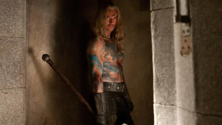 HD PC desktop wallpaper/background: scene from the movie Ironclad — shirtless, paint-smeared warrior leaning in a dim stone corridor, clutching a spiked mace.