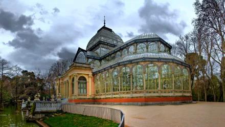 HD PC desktop wallpaper showcasing the man-made Palacio de Cristal with its intricate glass and metal architecture under a cloudy sky.
