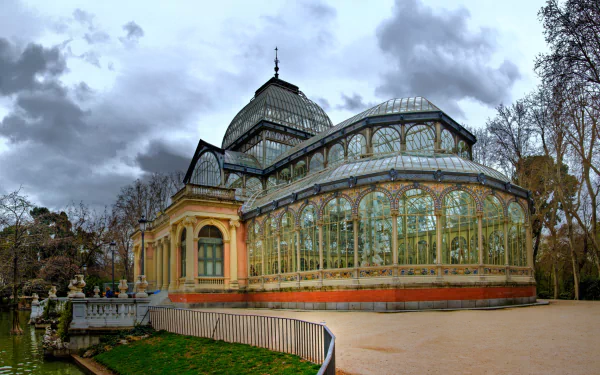 HD PC desktop wallpaper showcasing the man-made Palacio de Cristal with its intricate glass and metal architecture under a cloudy sky.