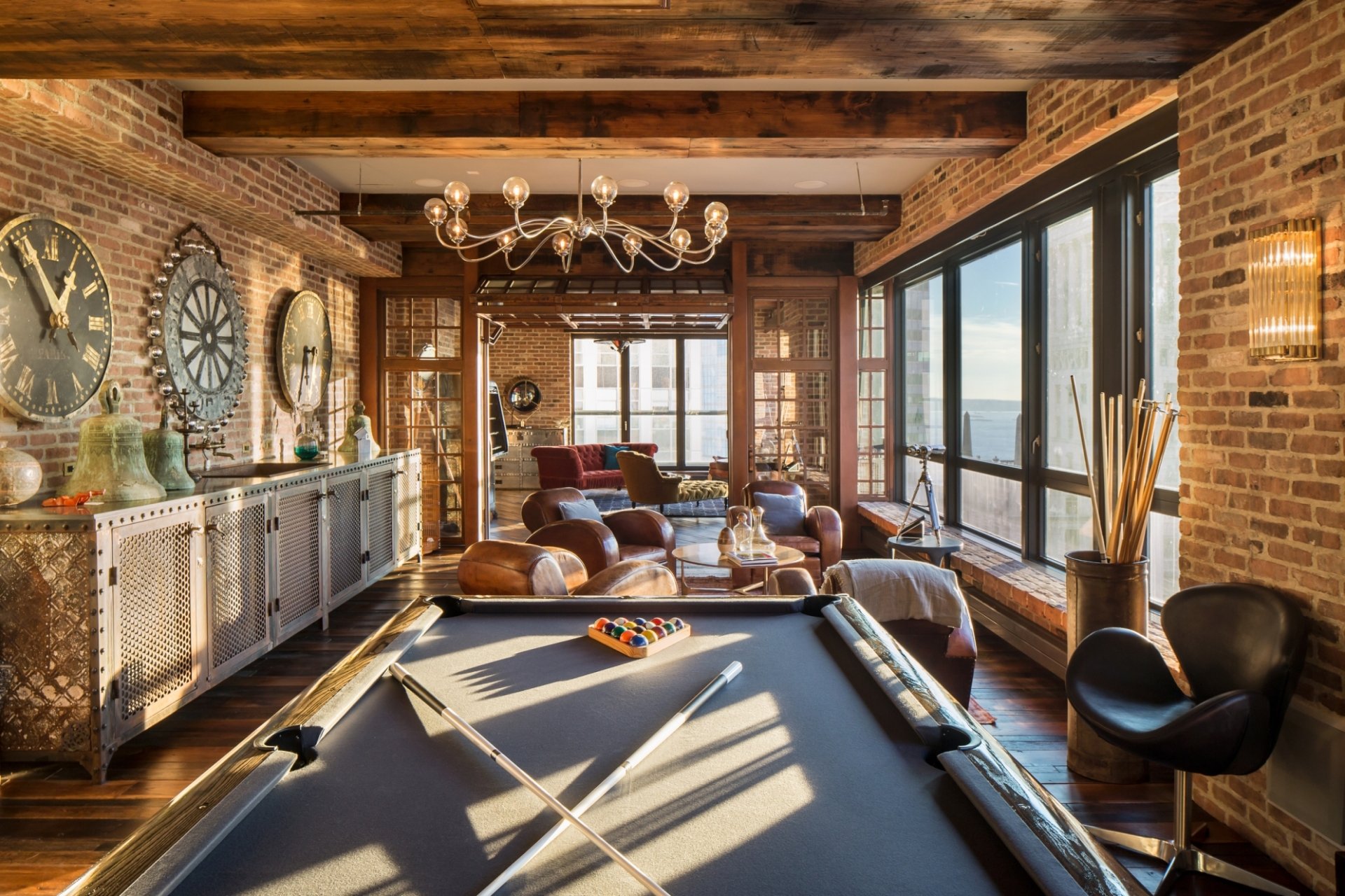 HD desktop wallpaper of a stylish man-made room featuring a pool table, exposed brick walls, large windows, leather seating, and rustic wooden beams.