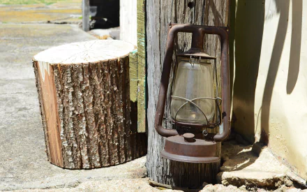 HD vintage desktop wallpaper showing a rusty old man-made lantern beside a textured wooden log, capturing nostalgic charm in natural light.